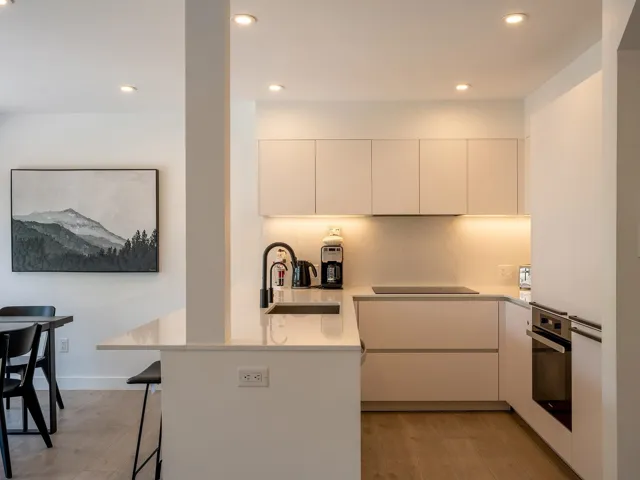 Kitchen featuring oven, black electric cooktop, light wood-style floors, a kitchen bar, and a sink