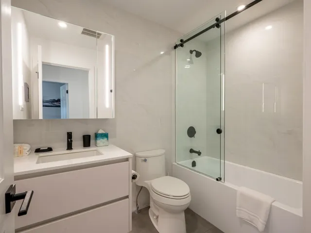 Bathroom with visible vents, decorative backsplash, toilet, enclosed tub / shower combo, and tile walls