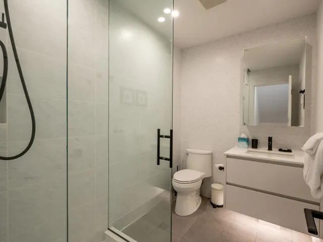 Bathroom featuring visible vents, toilet, tile patterned flooring, a tile shower, and vanity