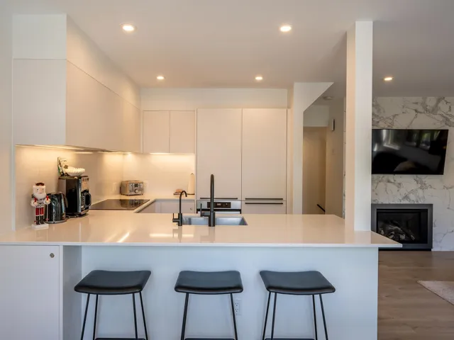 Kitchen with a peninsula, a sink, light countertops, modern cabinets, and a kitchen bar