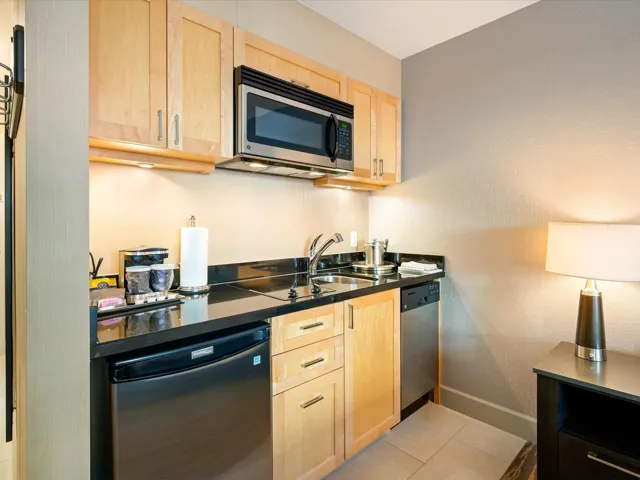 Kitchen featuring light brown cabinets, dark countertops, stainless steel appliances, and light tile patterned floors