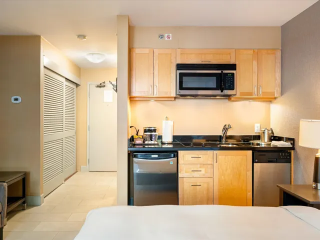 Kitchen with light brown cabinets, dark countertops, stainless steel appliances, and light tile patterned floors