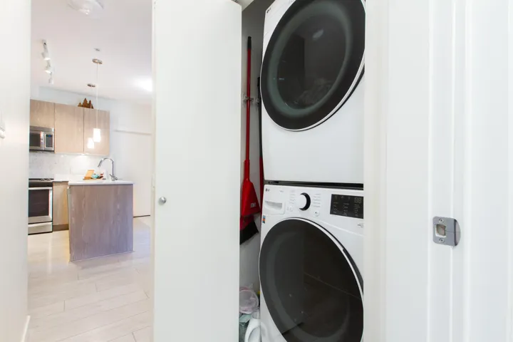 Laundry room with light wood-type flooring, stacked washer and clothes dryer, a sink, and laundry area