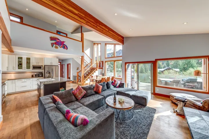 Living room with beamed ceiling, stairs, light wood finished floors, a high ceiling, and recessed lighting