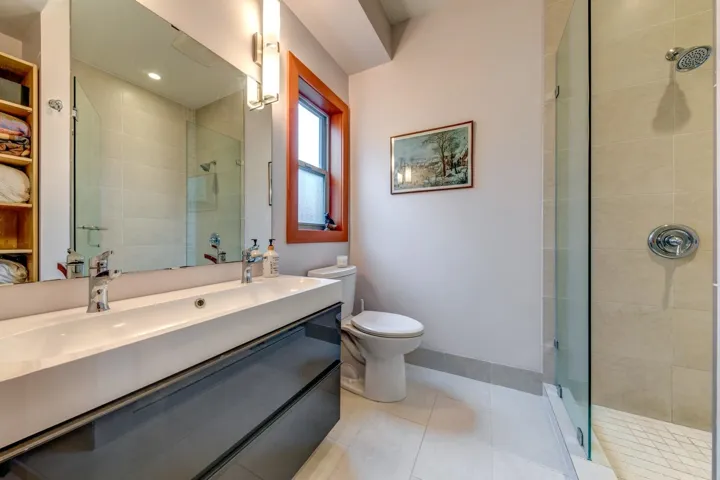 Full bathroom with a tile shower, tile patterned floors, toilet, and vanity