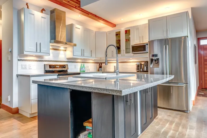 Kitchen with appliances with stainless steel finishes, wall chimney range hood, decorative backsplash, light wood finished floors, and recessed lighting