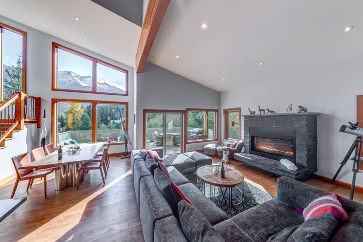Living room featuring wood finished floors, beamed ceiling, stairs, baseboards, and high vaulted ceiling