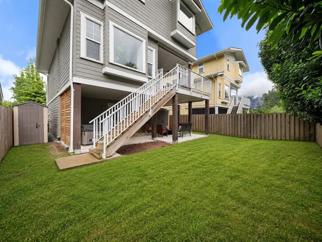 Expansive green lawn with a dedicated patio area, featuring a multi-level wooden deck with white railings