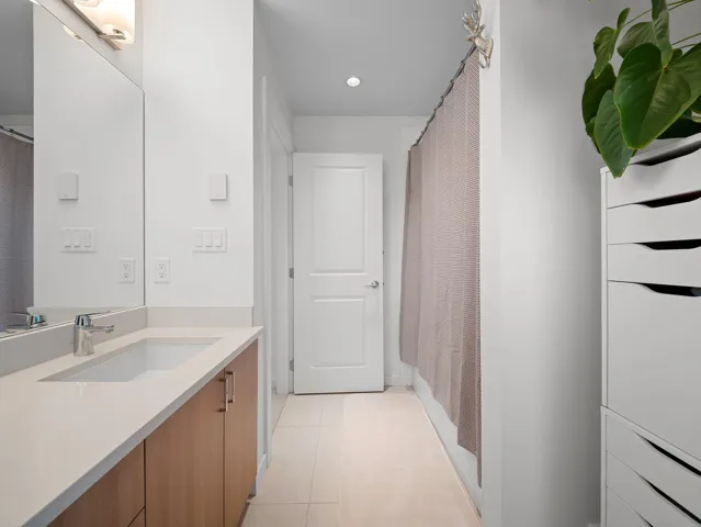 Bathroom featuring a light wood-finish vanity with an integrated rectangular sink, a light-colored countertop, and a large mirror