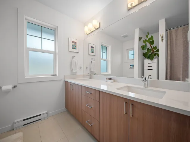 Dual vanity with wood-finish cabinetry and chrome hardware, featuring integrated rectangular sinks and a full-width mirror