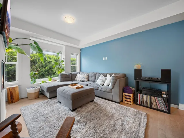 Living area featuring extensive window treatments, recessed ceiling, wood-finish flooring, and a vibrant accent wall