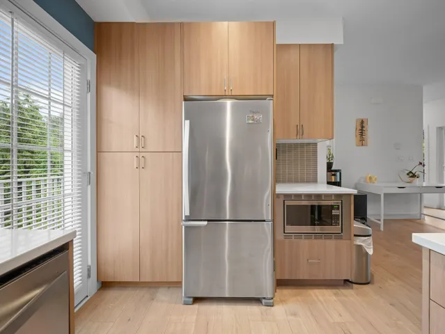 Kitchen featuring wood-finish cabinetry, stainless steel refrigerator, and wood-finish flooring