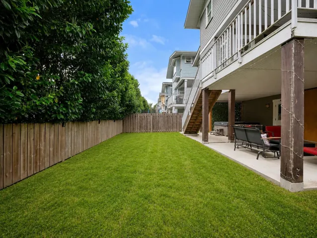 Expansive green lawn bounded by a wooden fence, featuring mature perimeter trees