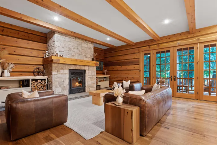 Living room featuring wooden walls, a fireplace, french doors, wood finished floors, and beamed ceiling