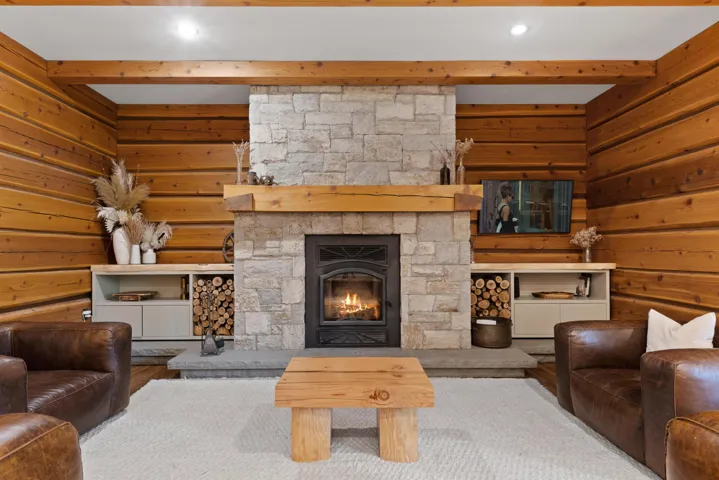 Living area featuring wood walls, wood finished floors, a fireplace, and beamed ceiling