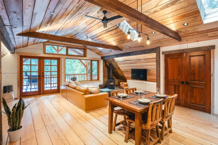 Dining area with a wood stove, ceiling fan, wooden ceiling, french doors, and light wood-style flooring