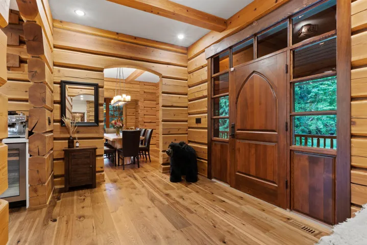 Foyer featuring beam ceiling, light wood-style floors, wood walls, recessed lighting, and wine cooler