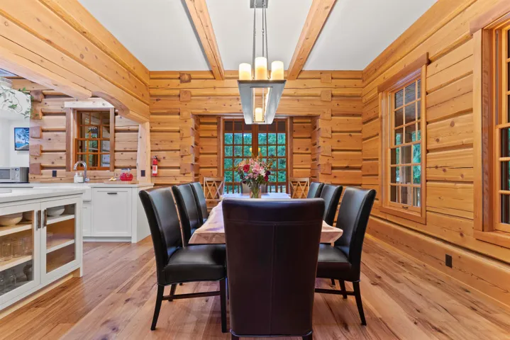 Dining room featuring wooden walls, beamed ceiling, and light wood finished floors
