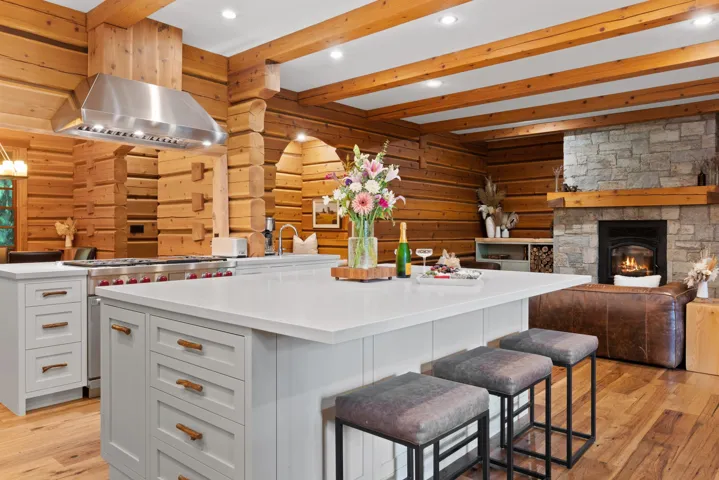 Kitchen with exhaust hood, a kitchen breakfast bar, a kitchen island, light wood-type flooring, and beamed ceiling