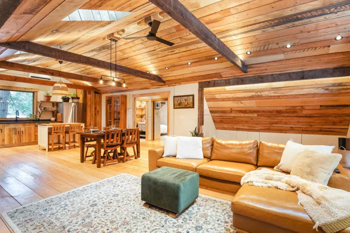 Living room featuring beamed ceiling, ceiling fan, wood ceiling, and light wood-style floors