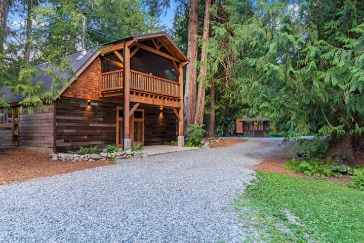 Log cabin with metal roof and gravel driveway