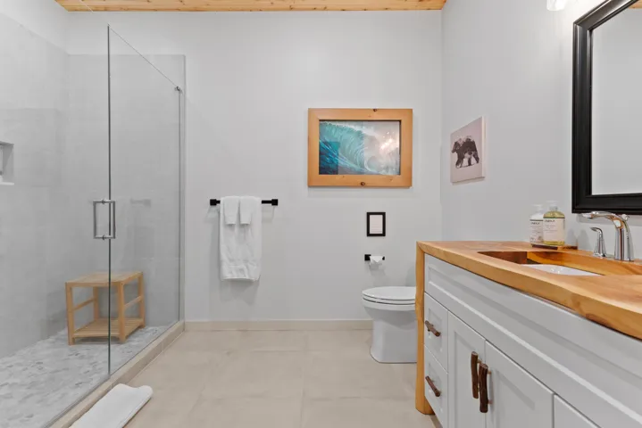 Bathroom with vanity, toilet, tile patterned floors, baseboards, and a shower stall