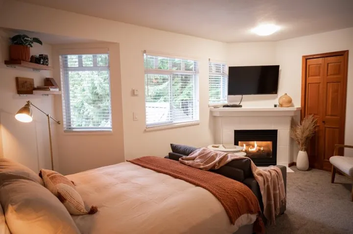 Interior space featuring a built-in fireplace, multiple windows with blinds, a wall-mounted television, and wood bi-fold closet doors