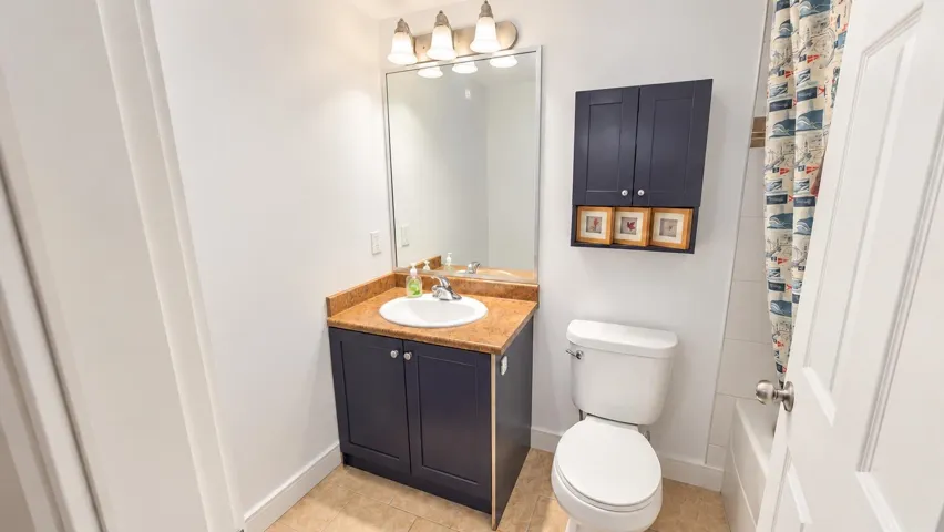 Compact bathroom featuring a vanity with dark cabinetry, integrated sink, and an overhead mirror