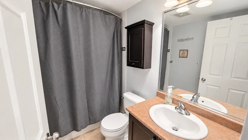Vanity with an oval sink and chrome faucet, large wall mirror, and a wall-mounted medicine cabinet