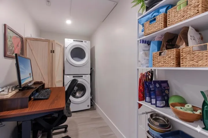 Dedicated laundry area featuring a stacked washer and dryer, wood-finish flooring, recessed lighting, and built-in shelving