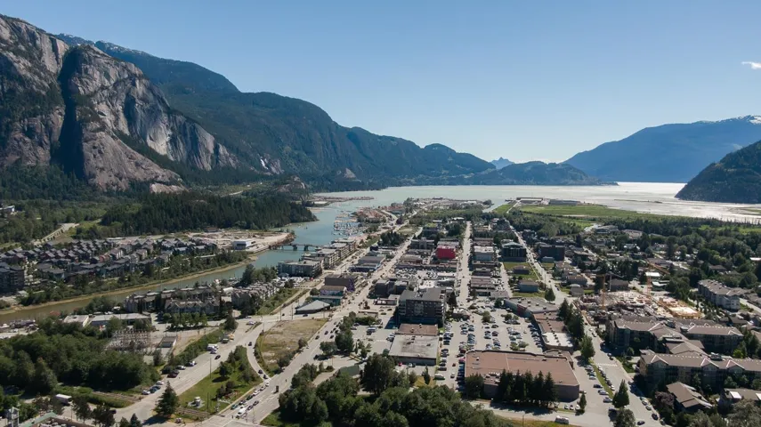 Aerial perspective showcasing a vibrant town with residential and commercial areas, bordered by a river and large body of water
