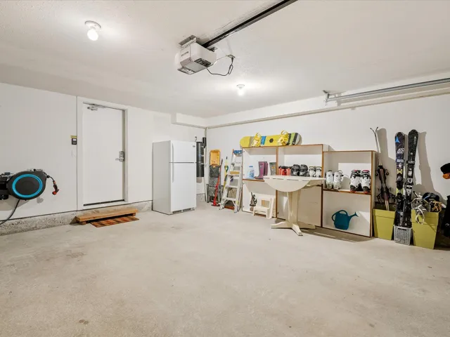 Garage featuring a garage door opener and freestanding refrigerator