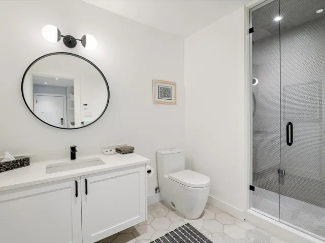 Bathroom with baseboards, toilet, vanity, tile patterned floors, and a stall shower