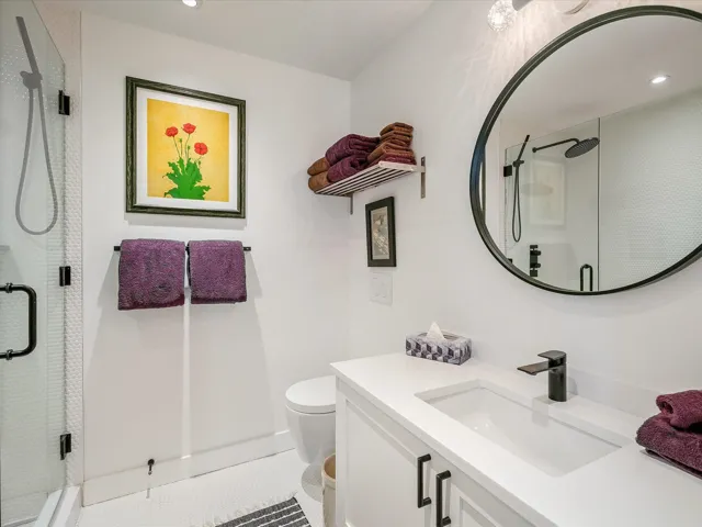 Bathroom featuring toilet, a stall shower, vanity, and tile patterned flooring