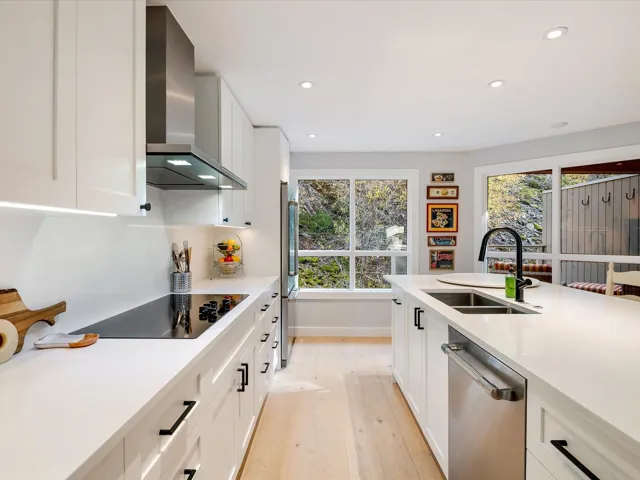 Kitchen with stainless steel dishwasher, refrigerator, wall chimney range hood, a sink, and black electric cooktop