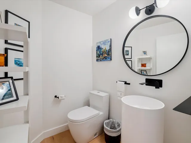 Bathroom featuring toilet, wood finished floors, and baseboards