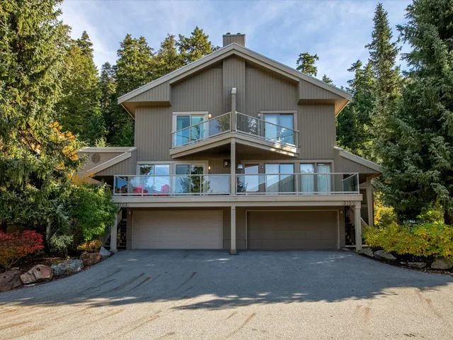 Chalet / cabin with a garage, stairs, a balcony, and driveway
