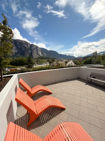 Spacious outdoor patio featuring concrete pavers, low perimeter walls, and distant mountain scenery