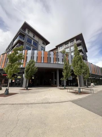 Contemporary mixed-use building featuring multi-level architecture, integrated retail spaces, and a covered entryway