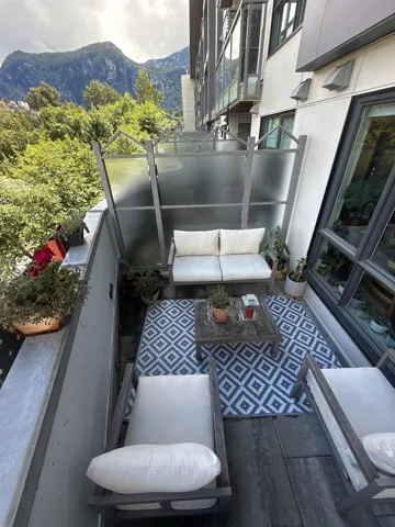 Balcony featuring wood-finish flooring, frosted privacy screens, and a mountain backdrop
