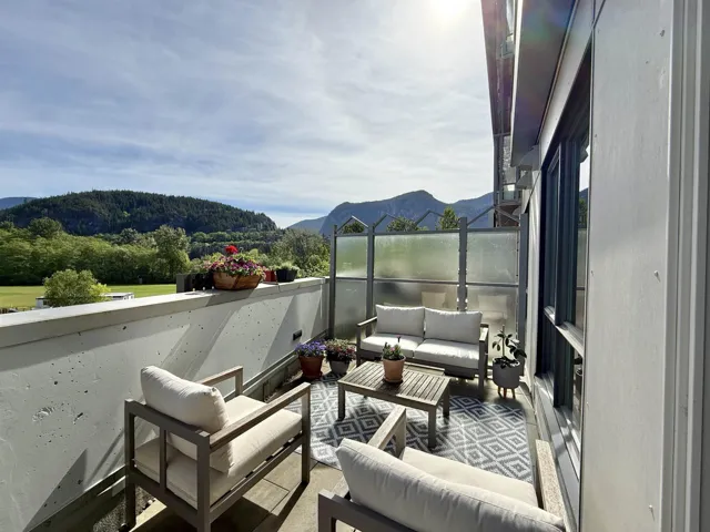 Spacious outdoor patio with a concrete barrier, privacy screen, and expansive mountain scenery