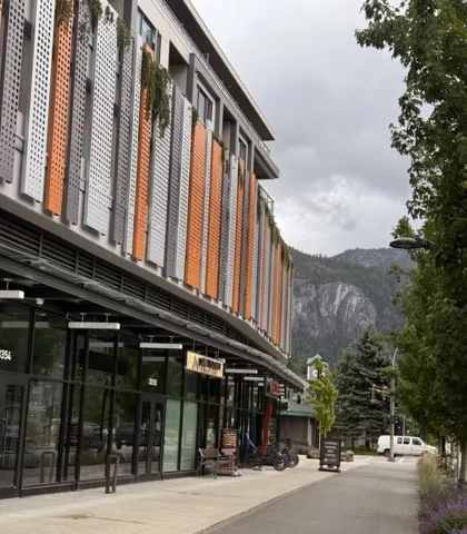Contemporary building facade featuring multi-colored perforated panels and integrated planters with greenery