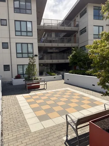 Community courtyard featuring a checkered paver design, perimeter seating, and built-in planters