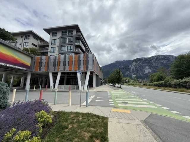 Multi-story building featuring modern architecture with balconies and a partial mountain backdrop