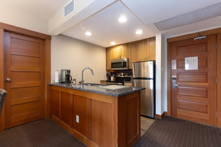 Kitchen with stainless steel appliances, a sink, a peninsula, dark colored carpet, and recessed lighting