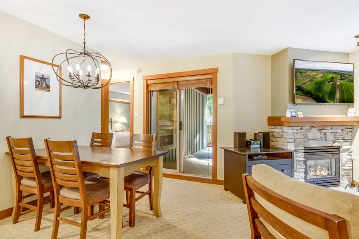 Dining area featuring a stone fireplace, light carpet, and a chandelier