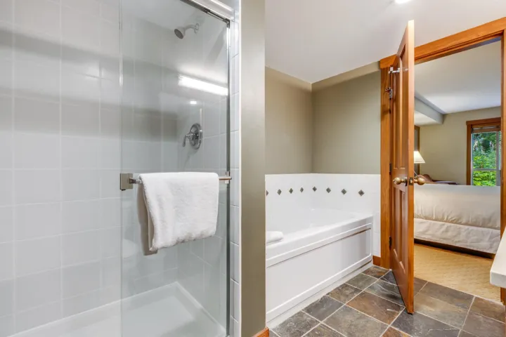 Ensuite bathroom featuring a stall shower, a garden tub, and stone tile floors