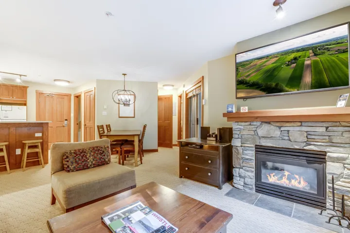 Living area featuring light carpet, a chandelier, and a stone fireplace