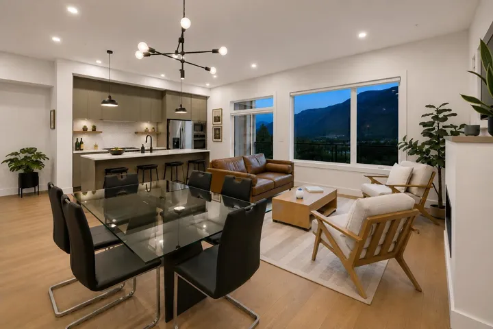 Open-concept living space featuring wood-finish flooring, recessed lighting, and large windows showcasing a mountain backdrop