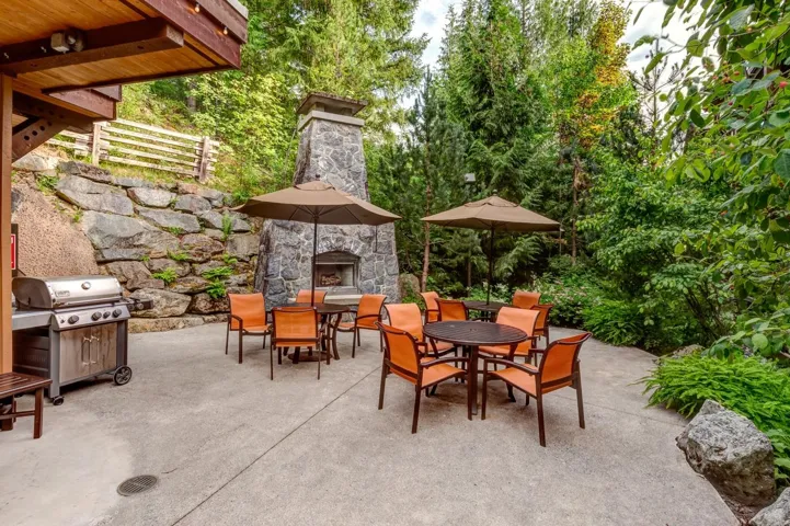 View of patio / terrace with outdoor dining space, an outdoor stone fireplace, and grilling area